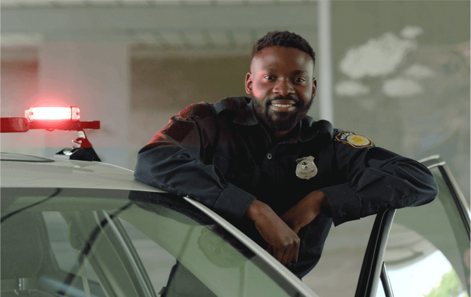 A smiling police officer leans out of a police car